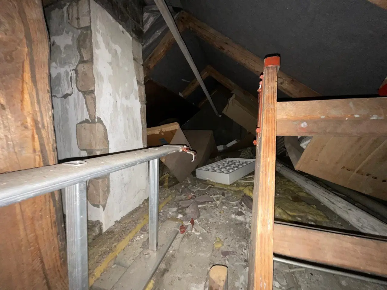 Dachboden mit Holzbalken, Geländer und abgestellten Gegenständen