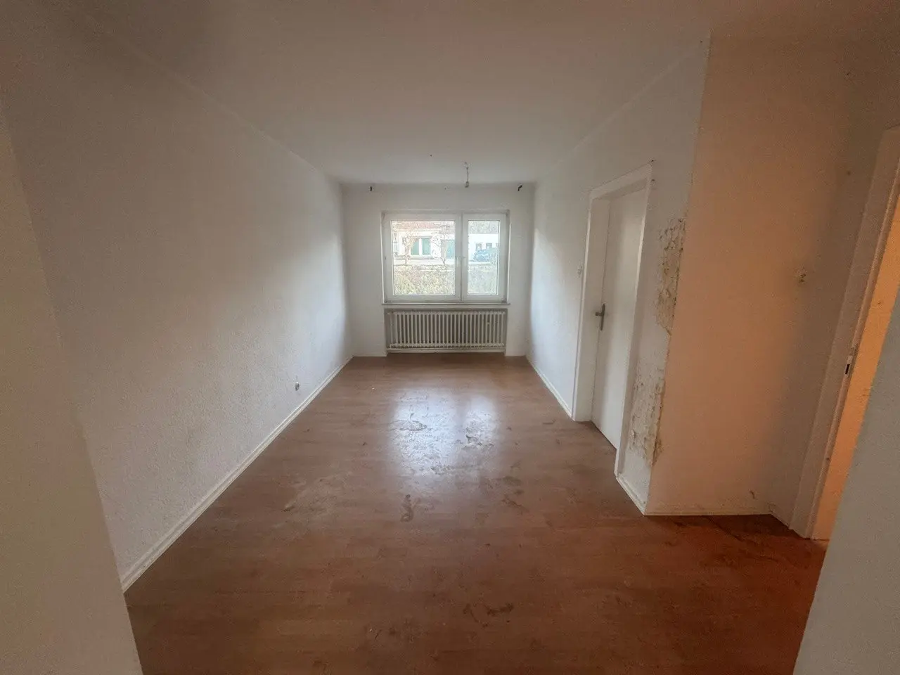 Leerer Raum mit Dielenboden und hellen Wänden nach der Entrümpelung