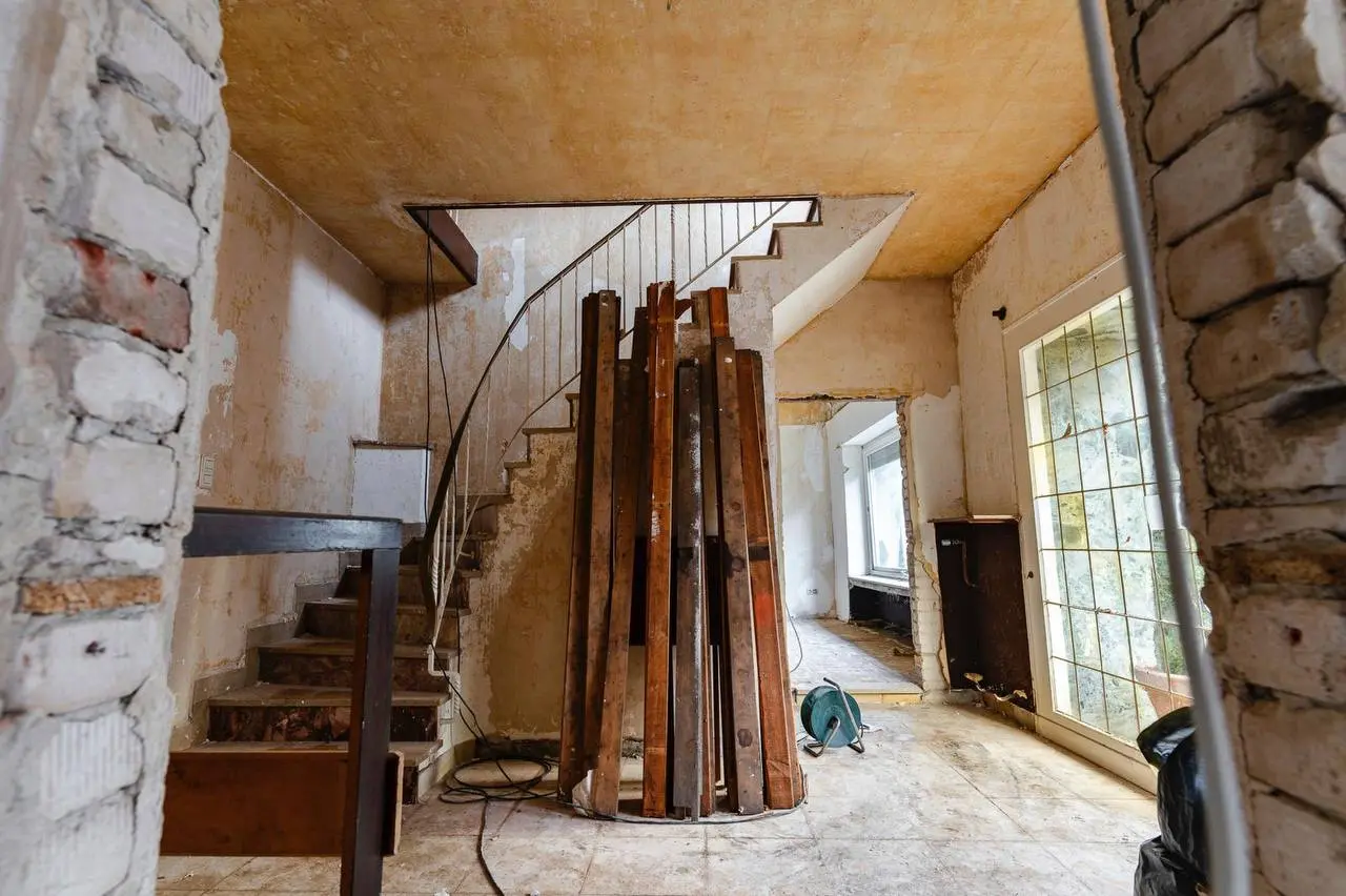 Holztreppe in einem entkernten Haus, davor senkrecht abgestellte Holzteile