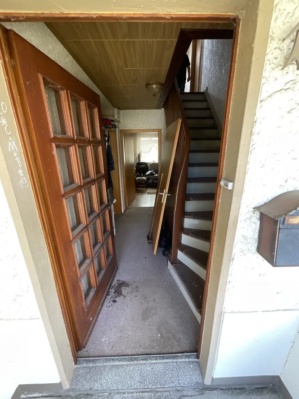 Offene Holztür mit Blick auf eine schmale Treppe