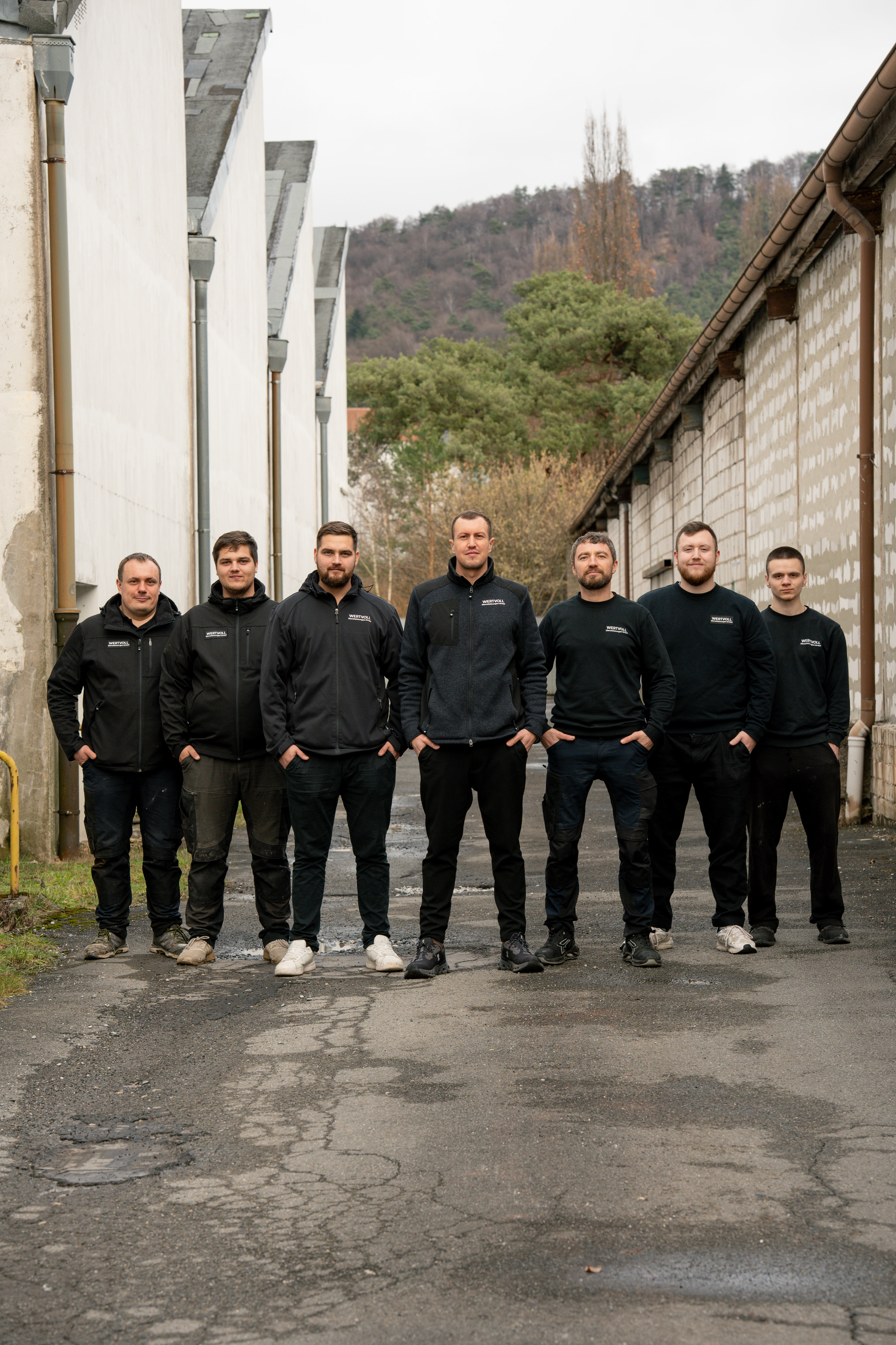 Das Team der Wertvoll Dienstleistungen GmbH in schwarzer Arbeitskleidung vor einer Hausfassade
