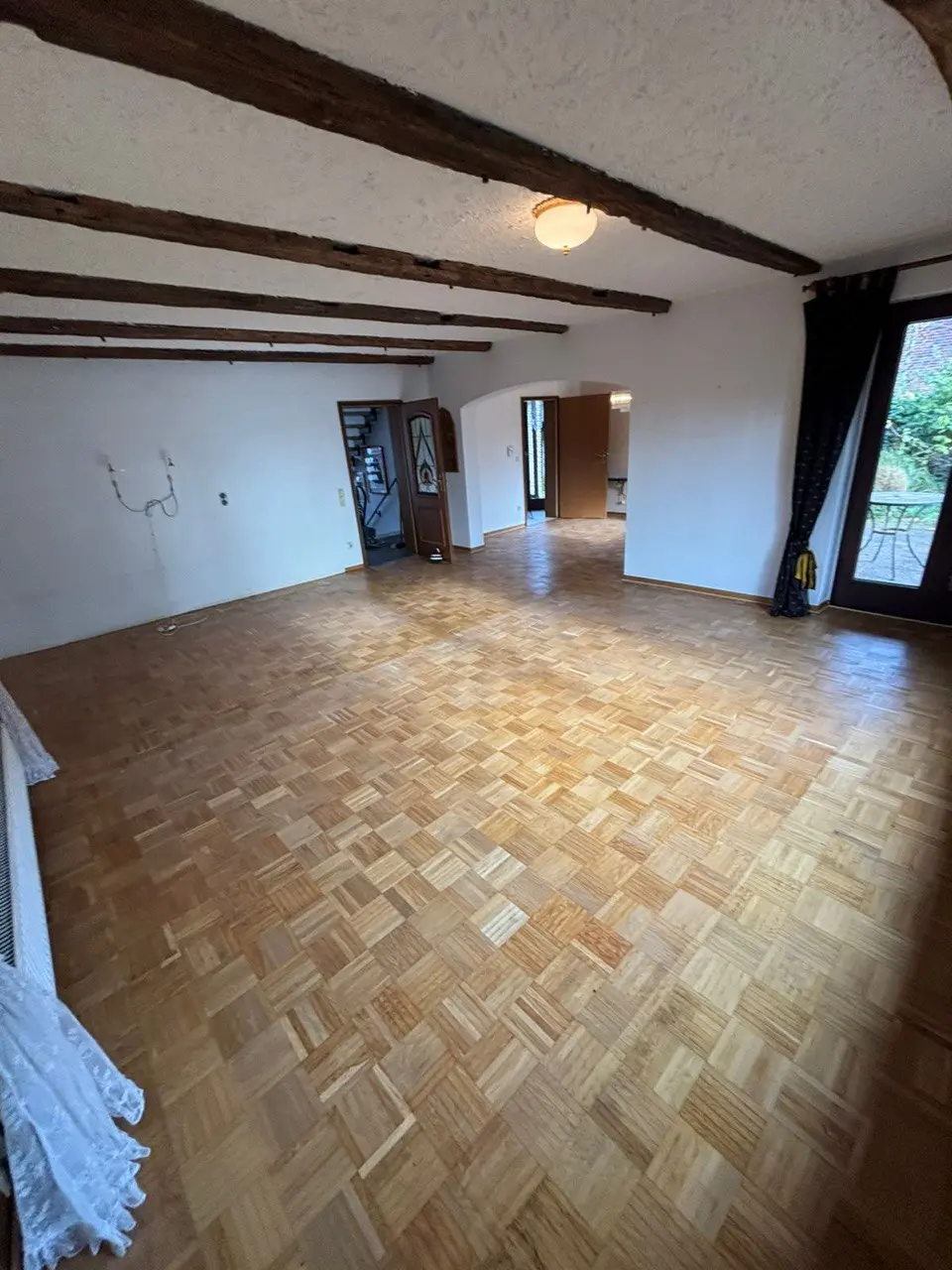Leerer Raum mit Holzbalkendecke und Parkettboden